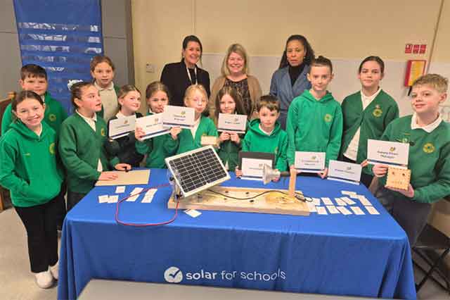 a group of pupils and some staff in a school stand for a group photo
