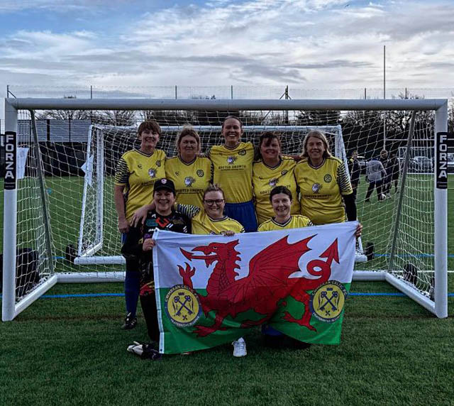 a women's football by goals hold a Wales flag