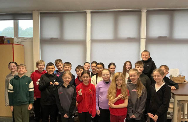 a class of school pupils smile for a photo
