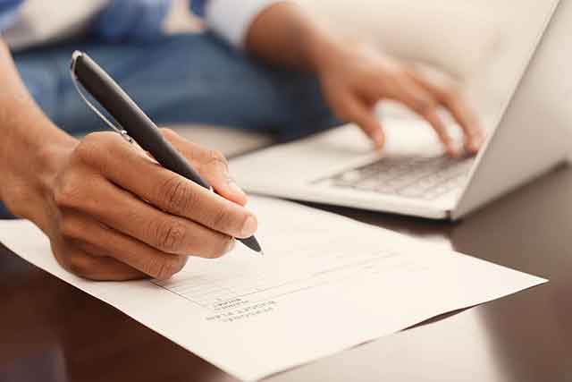 a man making financial report, making notes and working on laptop computer, closeup
