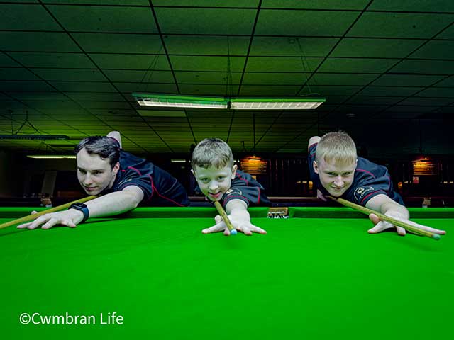 three young boys taking a shot on a snooker table