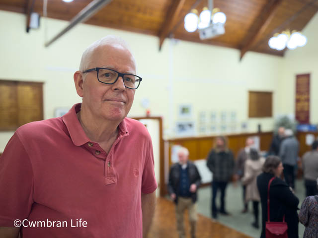 a man in a room with paintings on the wall