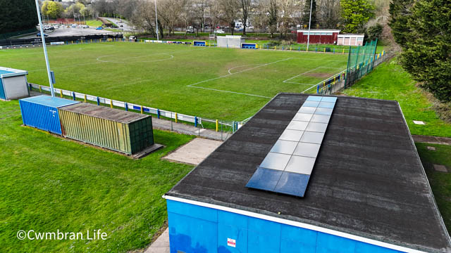 solar panels on the roof of a building next to a football pitch