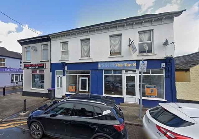 a former tanning shop with cars parked outside it