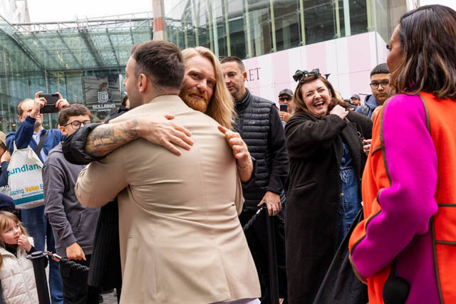 two men hug each other watched by others