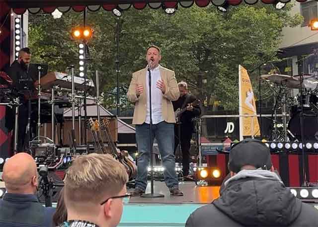 a man singing on a stage in front of a crowd
