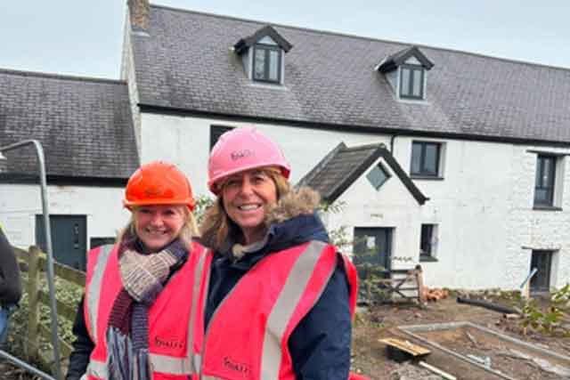 two women in hard hats outside a white building