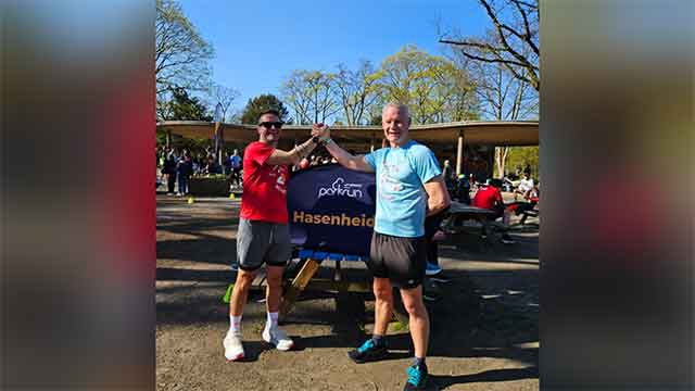 two men do a high five at a running event on a sunny day