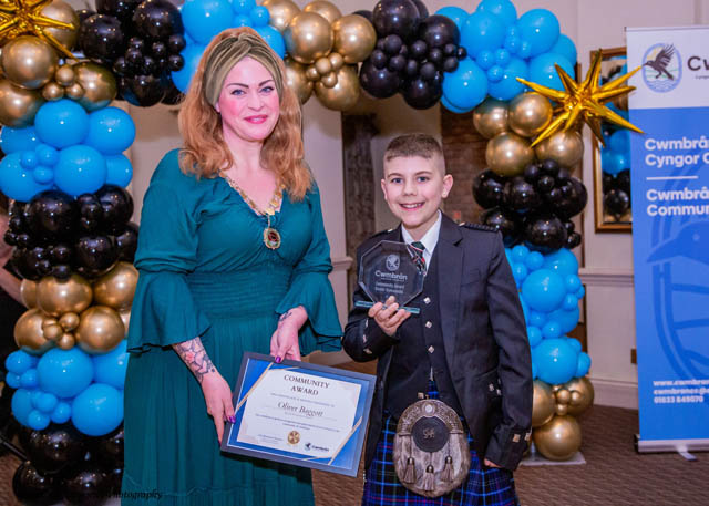 a woman and a young boy hold a certificate by a balloon arch