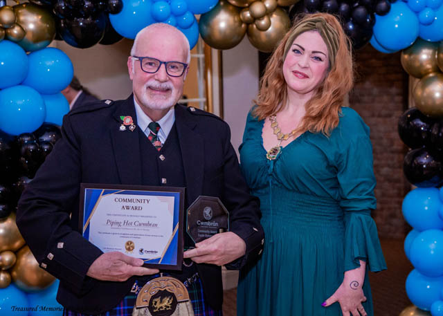a man and a woman hold a certificate in front of a balloon arch