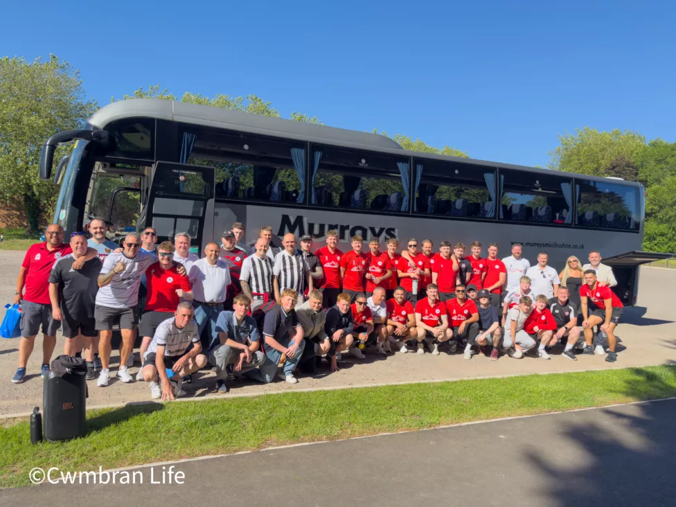 a group of football players and fans stood by a bus