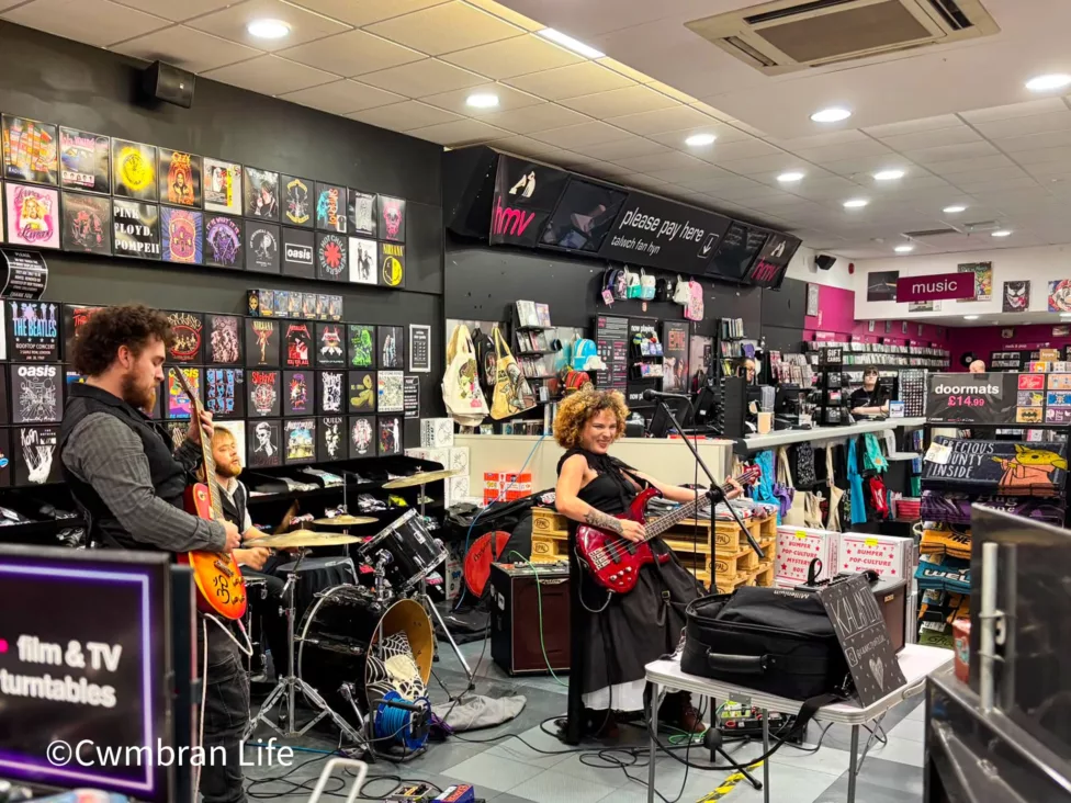 a band play a gig in a music store- the lead singer is holding a guitar