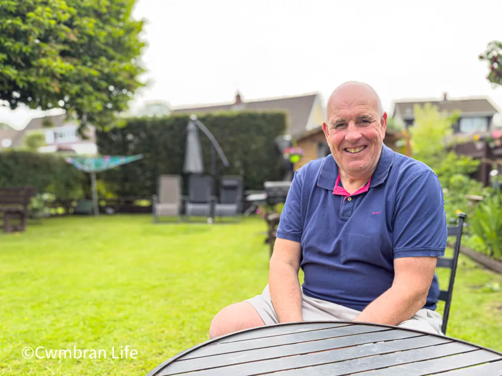 a man sat on a chair by a table in a garden