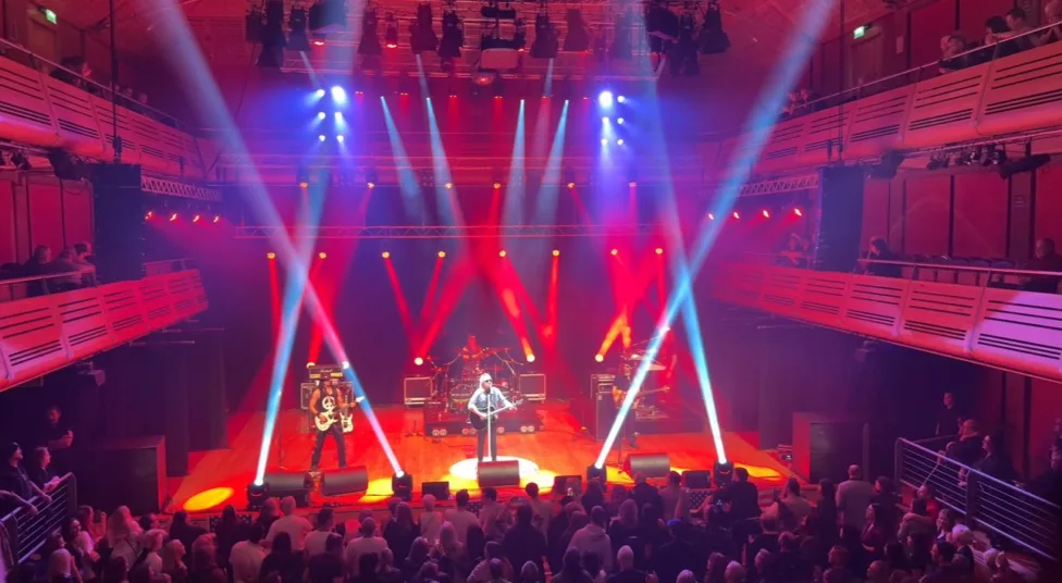 a band on stage playing to crowd with bright lazer lights across the stage