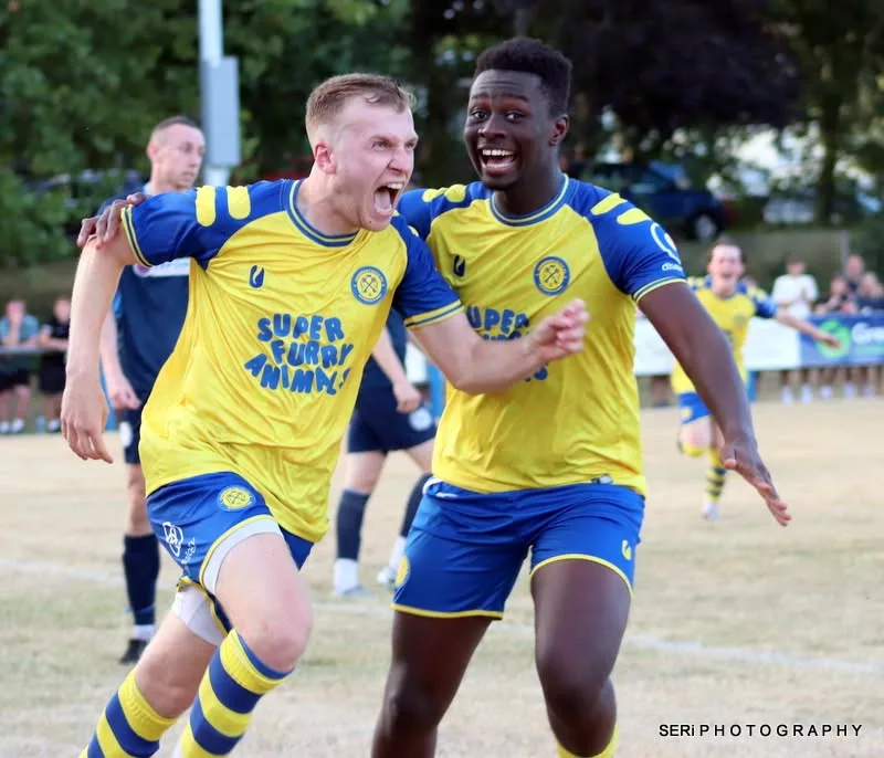 two footballers run and celebrate a goal