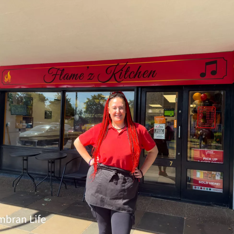 a woman outside a shop called Flame'z Kitchen