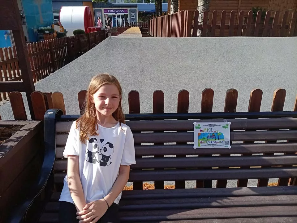 a girl sitting on a wooden bench