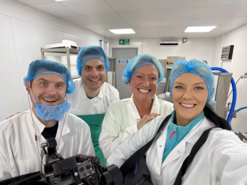 four people stood in a cheese dairy in white outfits and hair nets