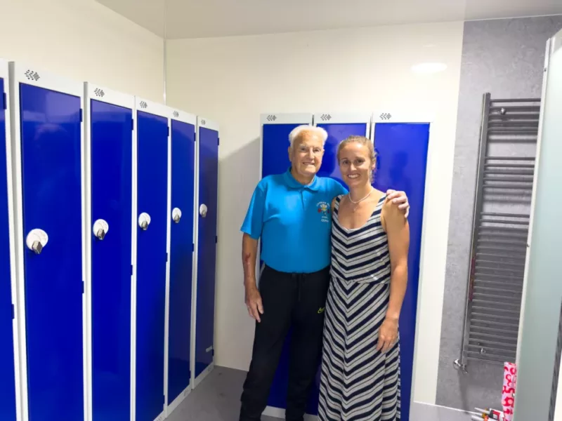 a man and a woman in a changing room stood by some blue lockers