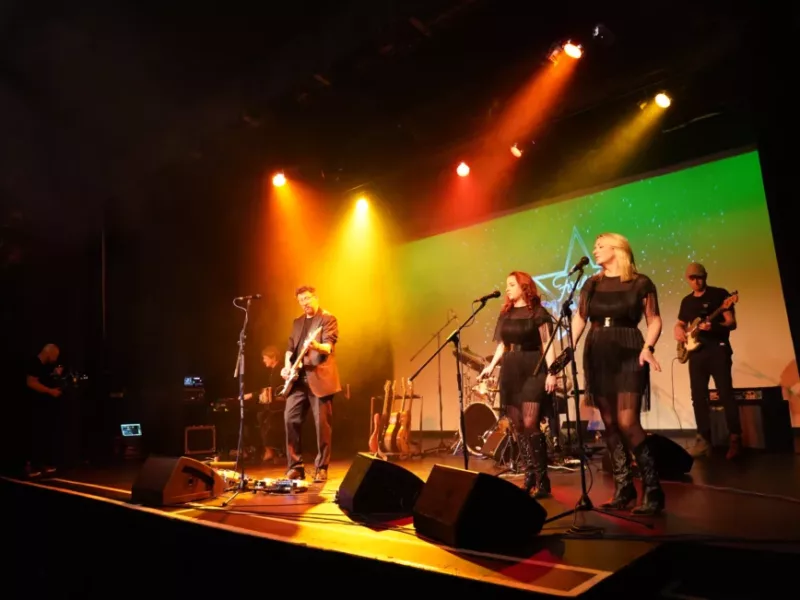 A singer/ guitarist on stage performing with backing singers