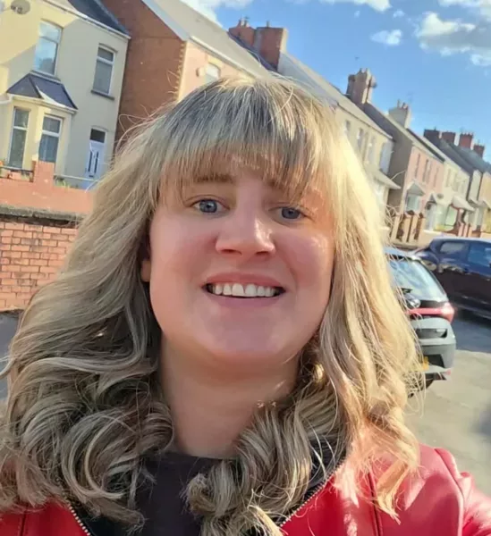 a woman stood in a street of houses smiles at the camera
