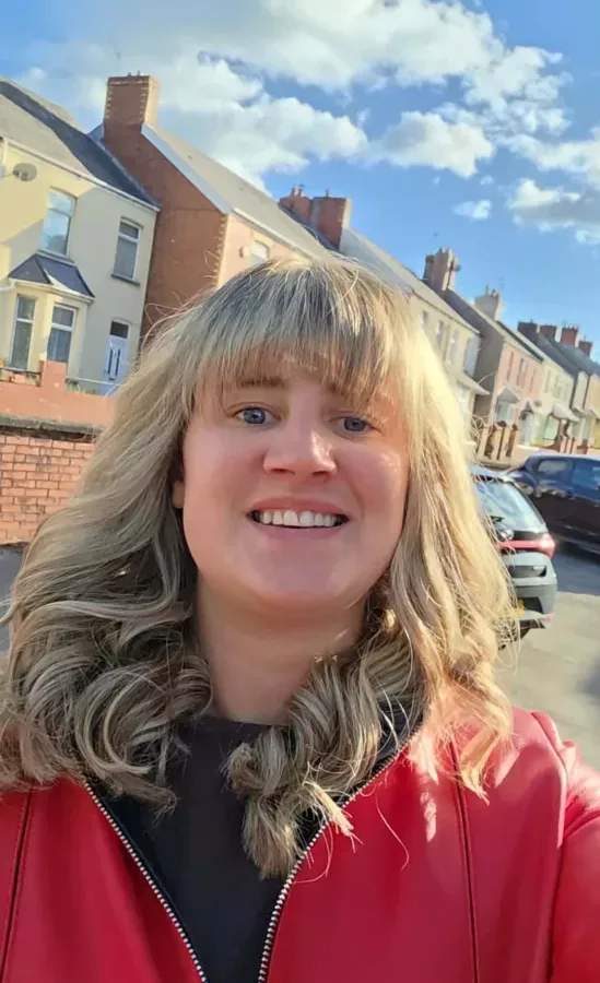 a woman stood in a street of houses smiles at the camera