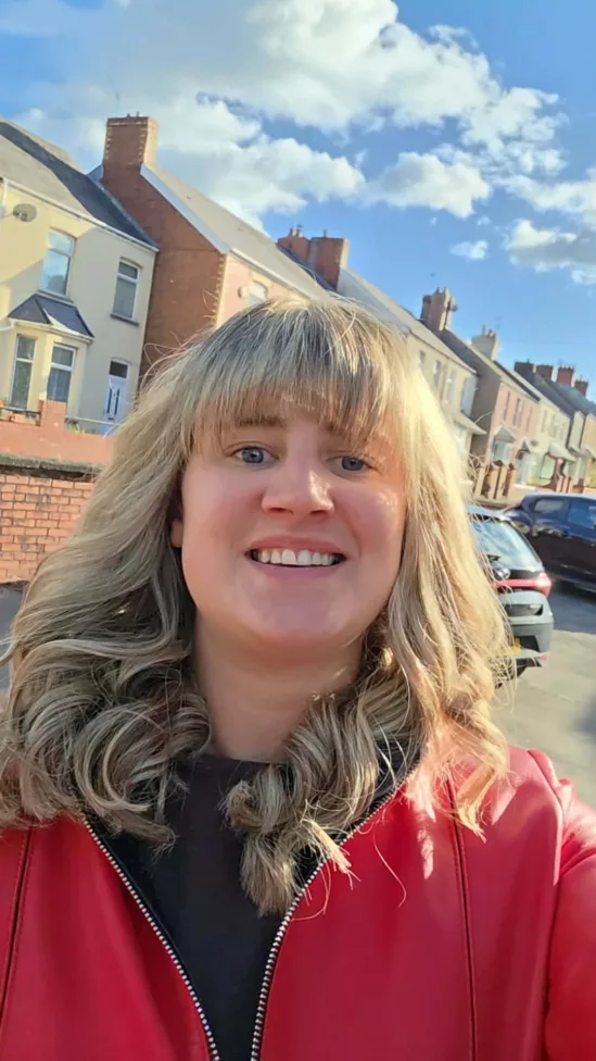 a woman stood in a street of houses smiles at the camera