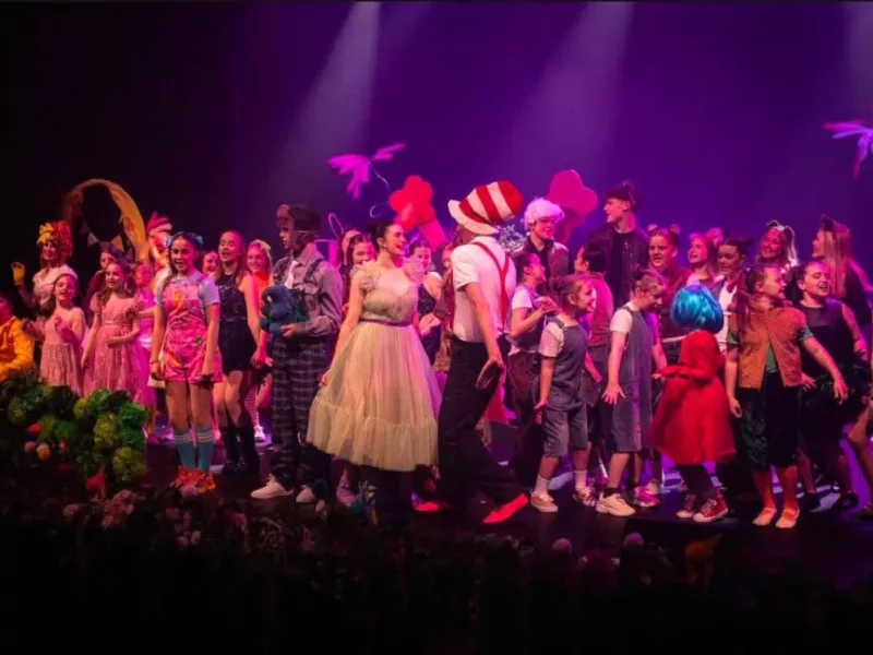 a large group of young people perform on a theatre stage
