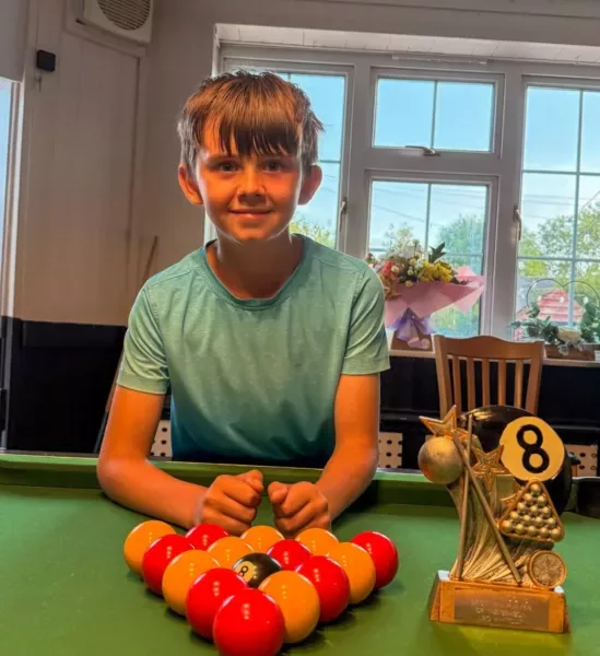 a young boy stood at a pool table