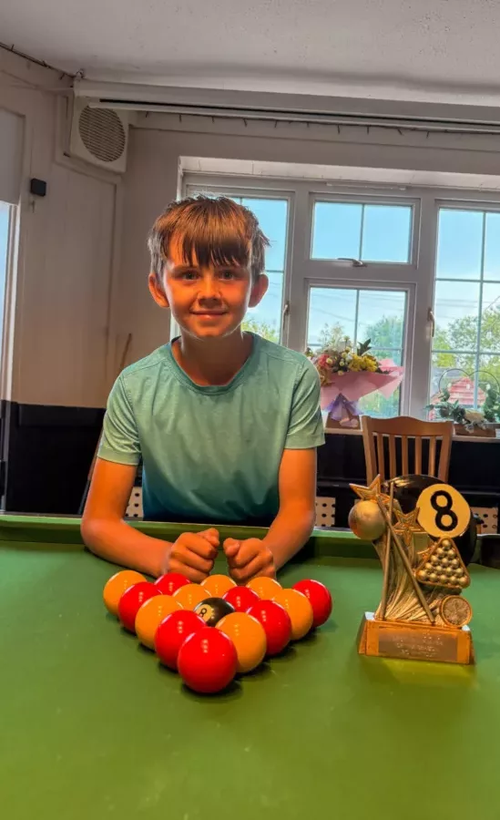 a young boy stood at a pool table