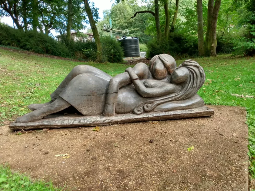 a sculpture of a man and women laying down in a park